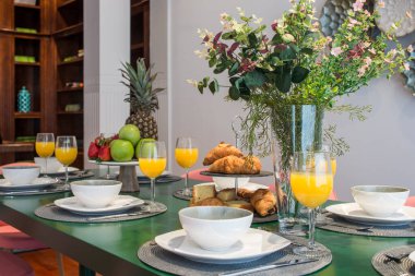 İçinde portakal suyu, taze meyve ve süs eşyası olan yeşil yemek masalı oturma odası.