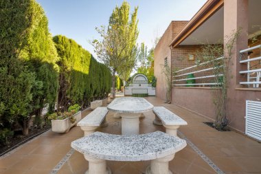 Kahverengi taş kaplama döşemeleri olan tek bir aile evindeki taş masalar ve banklar ile dinlenme ve dinlenme alanı