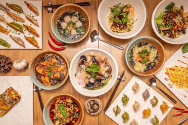 Tipik Japon yemek tarifleri, çeşitli ramen çeşitleri, kızarmış gyozalar, pişmiş gyozalar ve pandalarda tahta çubuklar.