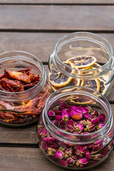 Glass jars with dried roses, dried hot peppers and dried orange slices