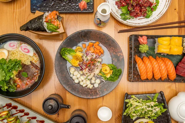 stock image Japanese fish recipes with the eternal sushi, salmon sashimi, a ramen with meat and vegetables and a Peruvian sea bass ceviche in the center