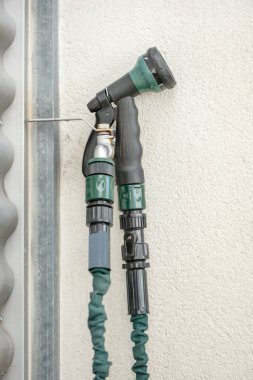 Terasta duvara bağlanmış bir hortumun musluğundan kaymak boyalı bir duvarla.