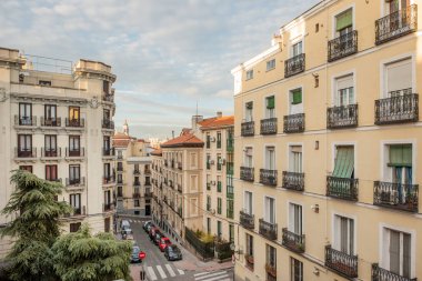 Madrid 'in tarihi merkezindeki eski yerleşim yerlerinin cepheleri kaldırımları, zebra yürüyüşleri ve bulutlu mavi gökyüzü ile caddelerde.
