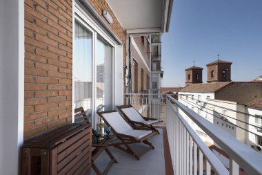 Dinlenmiş hamakları ve verniklenmiş ahşap masaları olan kiralık bir tatil evinin terası.