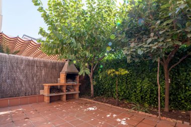 Çalı çitleri ve şömine ızgarası olan tek kişilik bir evin arka bahçesi.