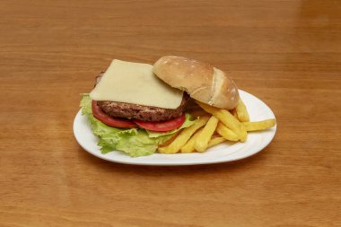 Klasik ve mütevazı sığır burger, bir dilim peynirli ve domates dilimli köy ekmeği.