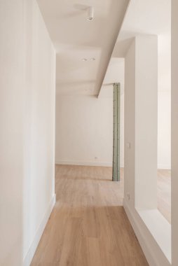 Geniş açık alanlı giriş salonu, eski metal sütunlar ve pürüzsüz yüzeyli minimalist tasarım ve ahşap taş kaplama döşeme.