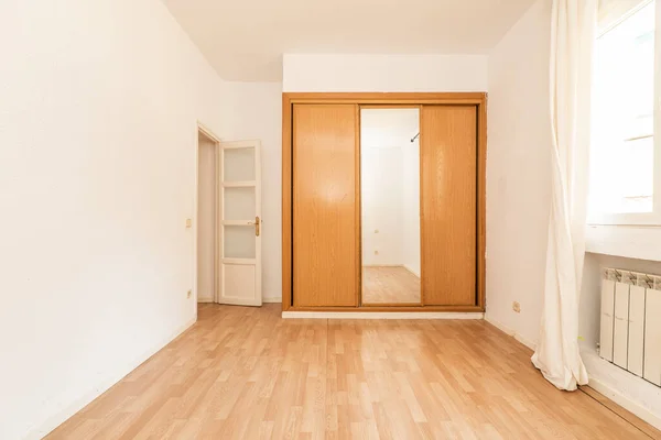 木製と白い木製のドアと積層床と組み合わせたスライドミラードア付きのワードローブが組み込まれた空の部屋 — ストック写真