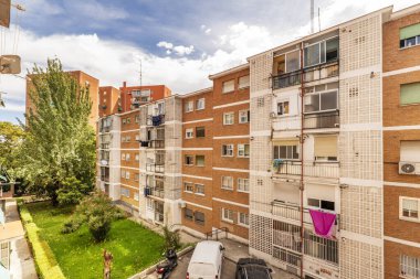 Güneşli bir günde beyaz, tuğlalı cepheleri ve bahçeleri olan eski apartman binalarının cepheleri.