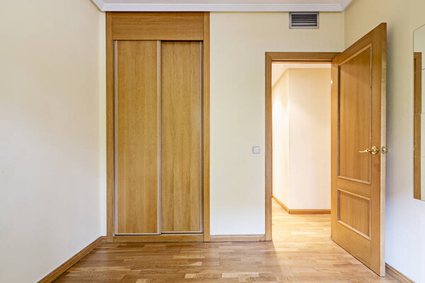 Bedroom in an empty room with a mirror attached to the wall, ducted air conditioning and French oak flooring and an entrance door of the same material and a long corridor with access to other rooms