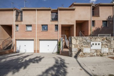 Beyaz metal garaj kapıları olan, yarı müstakil, tek aile konut binalarının ön cepheleri.