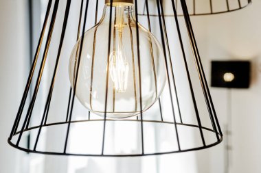 Dekoratif lambaları yakın. Oturma odasının tavanından sarkan büyük ampuller var.