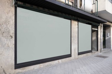 İki beyaz cam penceresi, soluk mermer duvarları ve siyah boyalı çelik kenarları ve caddeleri olan bir ticari binanın önü geleneksel döşemelerdir.