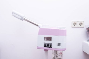 Güzellik merkezinde tedavi uygulamak için pembe ve beyaz tekerlekli bir makine.