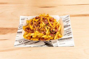 Kızarmış domuz pastırması, maydanoz ve çedar soslu bir tabak doğranmış cips.