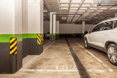 Boş park yerleri ve sütunlarda sürtünmeye karşı uyarıları olan bir garaj.