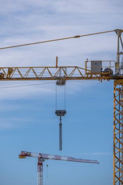 Zincirli kancalı binaların yapımı için farklı renklerde çeşitli kentsel metalik vinçler dağınık bulutlu açık bir gökyüzü günü