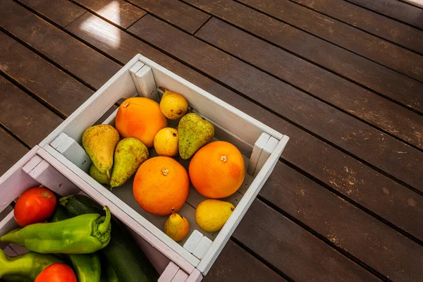 A few wooden boxes full of delicious and healthy fresh fruit and vegetables on a dark brown wooden surface