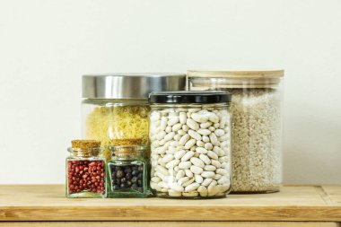 Farklı baharatlar, pirinç, çorba macunu ve beyaz fasulyelerle dolu cam kavanozlar.