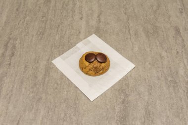 Gri bir yüzey üzerinde iki yuvarlak siyah çikolata içeren lezzetli taze pişmiş çikolatalı kurabiye.