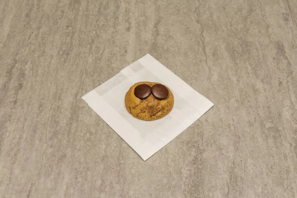 Gri bir yüzey üzerinde iki yuvarlak siyah çikolata içeren lezzetli taze pişmiş çikolatalı kurabiye.