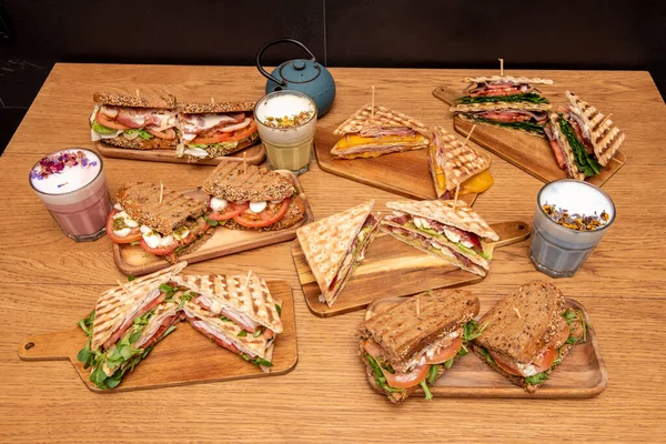 a lot of sandwiches and salmon sandwich, with tomato, pastrami, vegetables, mixed sandwich and antioxidant drinks