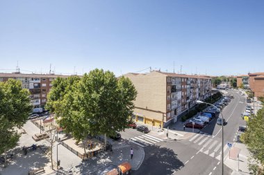 Ortalarında ağaçlar ve caddelerde zebra geçitleri olan kentsel binaların manzarası