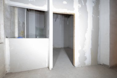 Yenilenmiş bir binada alçıdan duvarları olan ham oda ve elektrik kablolarını taşımak için plastik borular.