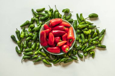 Yeşil biberler ve kırmızı biberlerle dolu beyaz bir yüzeyi olan güzel, sakin bir hayat.