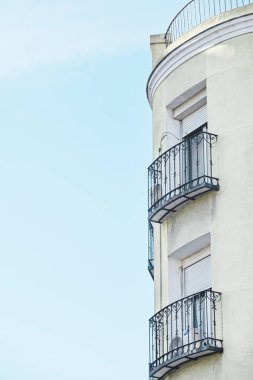 Sanatsal demiryolu döşenmiş balkonları olan bir binanın ön cephesi.