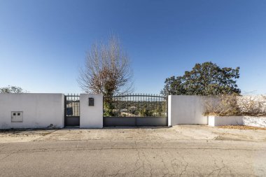 Birkaç metre arazisi olan tek bir aile evinin duvar ve giriş kapısı. Meşe ağaçları ve bahçeleri var.