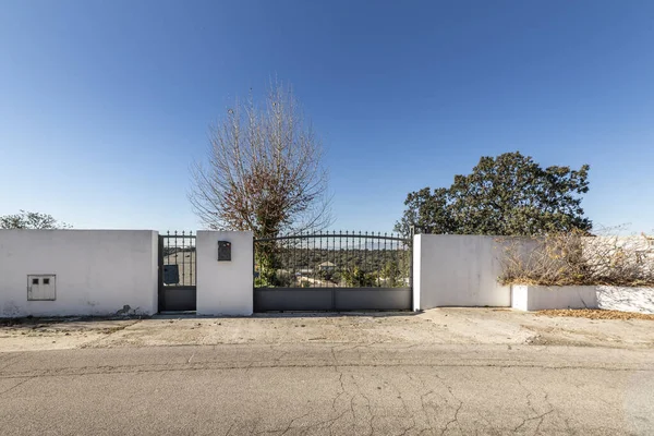 Birkaç metre arazisi olan tek bir aile evinin duvar ve giriş kapısı. Meşe ağaçları ve bahçeleri var.