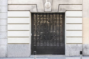 Facade of a vintage building with a security shutter at an entrance