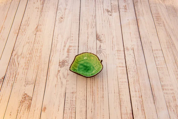 A pretty leaf green dip dish in the center of a wooden plank table
