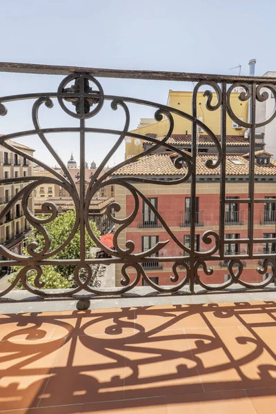 Balcony with artistic wrought iron railing painted black with a view of the center of the city of Madrid, Spain