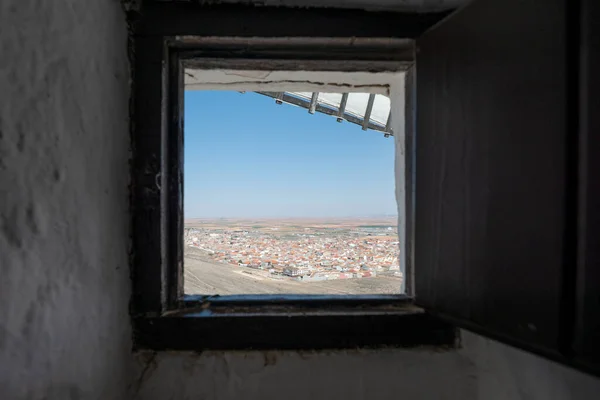 Square window of a windmill with blades and views of the town of Consuegra on the Don Quixote route in Spain