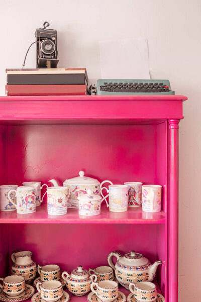 Pink painted sideboard with tea sets and vintage decorative items