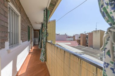 Narrow terrace balcony for access to homes with metal railing and green extendable curtains