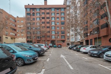 Main facade of clay brick urban residential houses with parking area with spaces marked with white paint