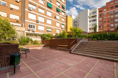 Common areas of the inner courtyard of the block with gardens, hedges, trees, stairs, litter bins and benches for the rest of the residents