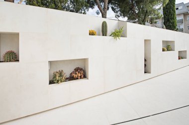 Marble wall of a plot with niches filled with various cacti