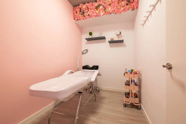 Massage cabin with folding table in a beauty salon with plain pink walls