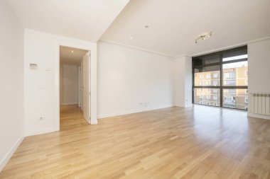 Living room of an empty house with oak parquet floors with a black anodized aluminum window and ceiling with plaster moldings