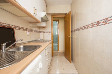 Small kitchen with white high and low cabinets with wooden details on the countertop and cornices