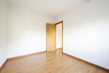 Small empty room with oak laminate flooring with matching skirting boards and doors