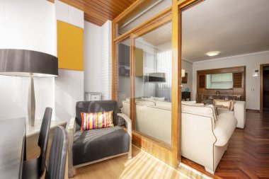 A small closed terrace with glazing next to a spacious living room with white sofas