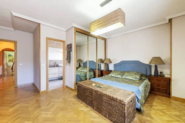 Bedroom with built-in three-section wardrobe, en-suite toilet and wicker trunks at the foot of the bed