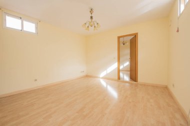 Empty living room with oak front door, ceiling lamp with glass shades and tall small windows