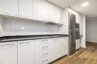 Newly installed white cabinet kitchen with integrated stainless steel appliances and black stone countertop