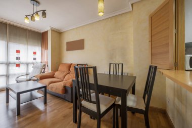 Small living-dining room with a square wooden table next to a serving hatch to the kitchen